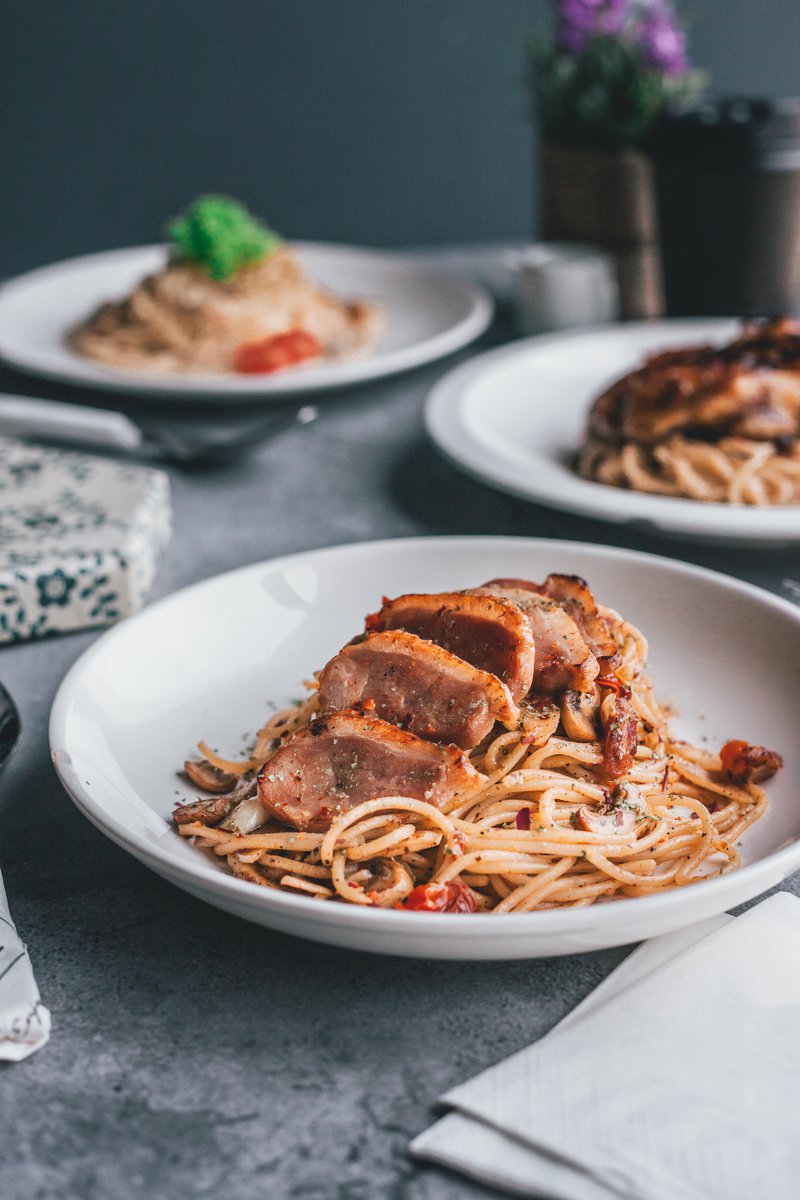 Three servings of tasty western chicken and smoked duck aglio olio pasta served on white ceremic plates. PIXERF