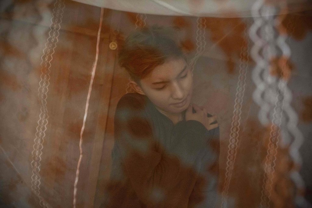 An intimate photo of a Chris, a trans woman from Myanmar, in her bedroom. 